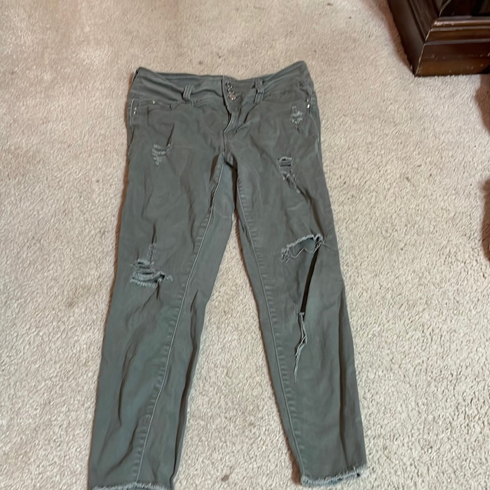 Army green, ripped mid-rise jeans.
